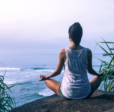 Kaya üzerinde sahilde Yoga pratik kadın 