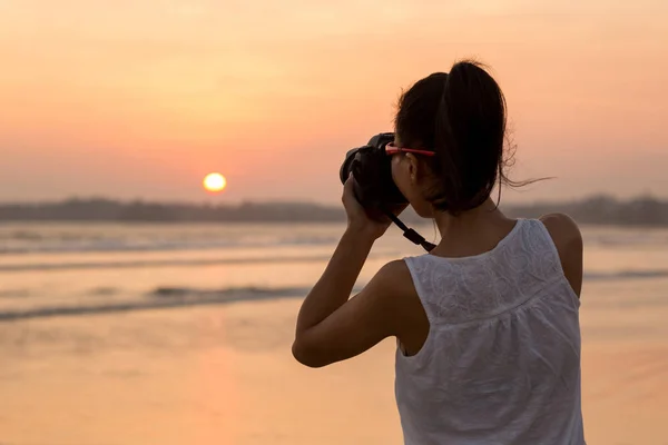 年轻的女摄影师拍摄海落时分 — 图库照片