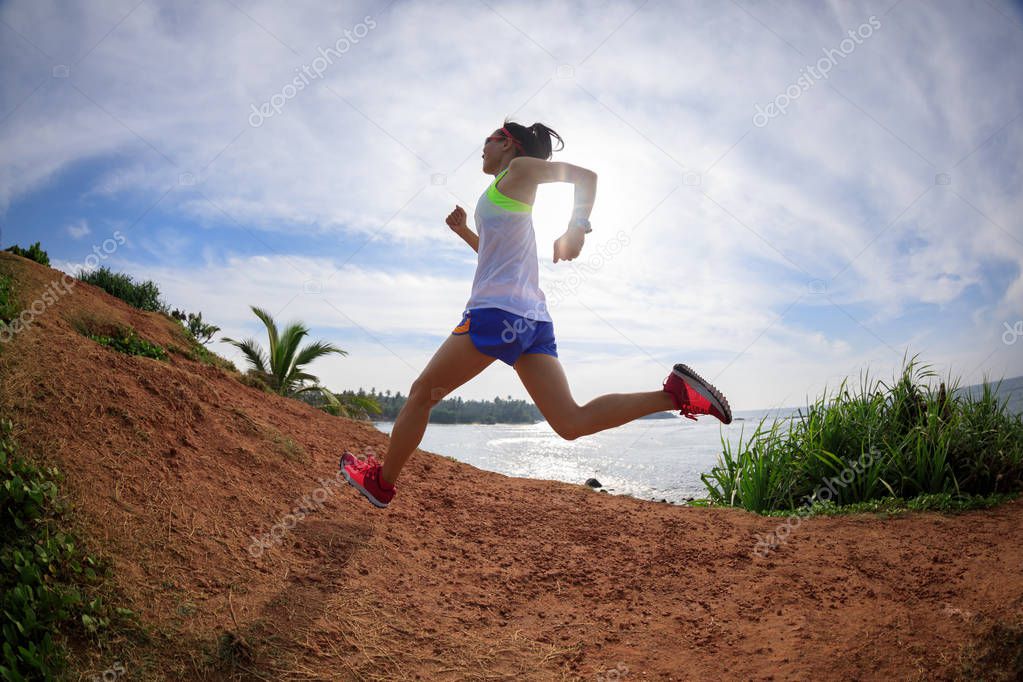 Woman trail runner running on seaside hill 