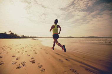 young fitness woman running at sunrise on beach 