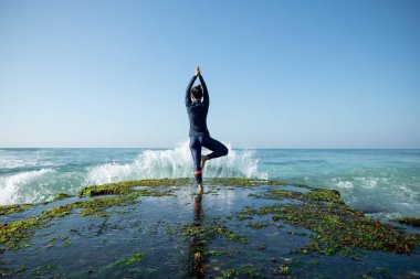Pratik yoga sahil mercan uçurumun kenarında genç kadın