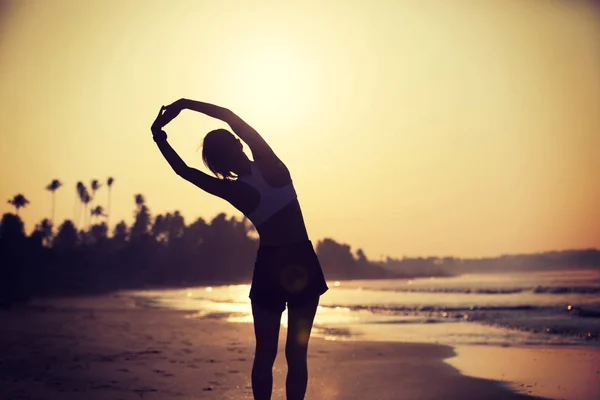 日の出ビーチで腕を伸ばすスポーツウーマン — ストック写真
