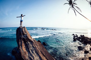 Başarılı kadın sahil kaya uçurumun kenarında kollarını uzattı