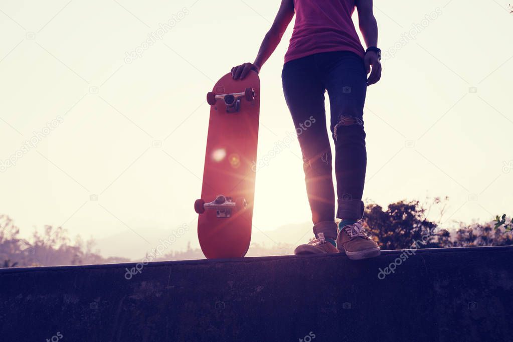 Skateboarder with skateboard standing at skate park