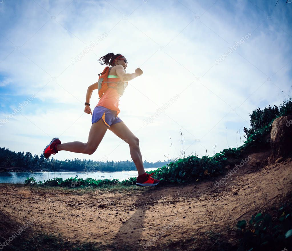 Woman trail runner running on seaside hill