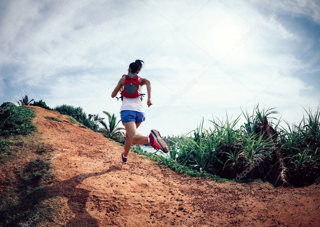 Woman trail runner running on seaside hill