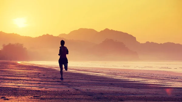サンライズビーチで走っている若いフィットネスウーマンのシルエット — ストック写真