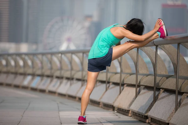 Healthy lifestyle woman runner stretching legs on foggy city morning
