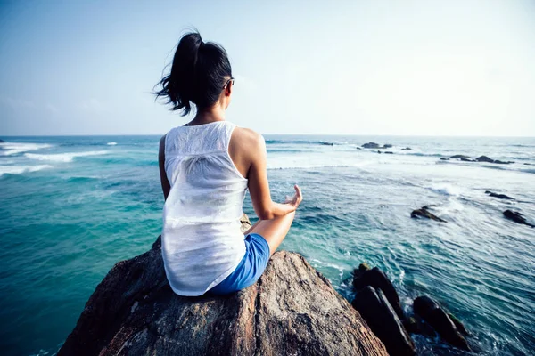 Genç yogacı kadın kayalıklarda meditasyon yapıyor.  