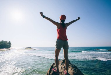 Sahil kaya kayalıküzerinde uzanmış kolları ile başarılı bir kadın  