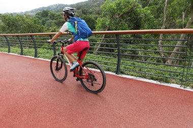Orman yolunda dağ bisikleti süren bir kadın.