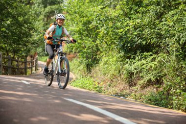 Orman yolunda dağ bisikleti süren bir kadın.