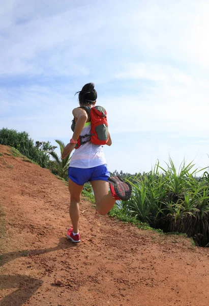 Woman trail runner running on seaside hills