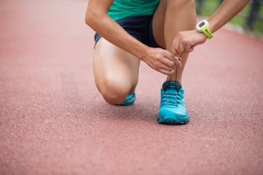 Koşucu atlet bahar ormanı patikası üzerinde ayakkabı bağı bağlama. egzersiz sağlıklı yaşam kavramı.
