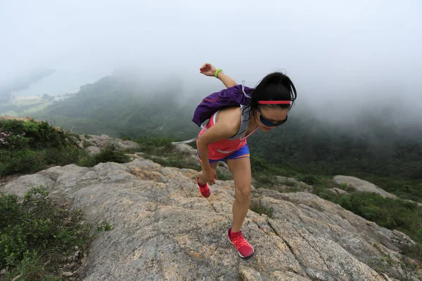 Young fitness woman running up at the mountain top