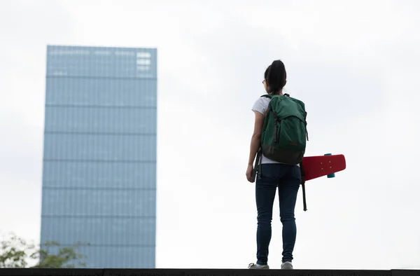 街でスケートボードを手に歩く女性スケートボーダー — ストック写真