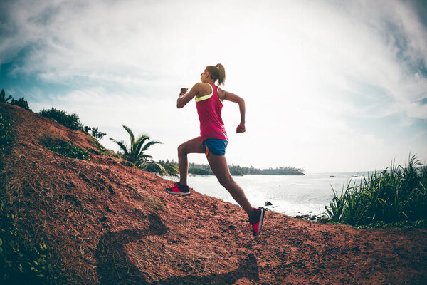 Woman trail runner running on seaside hills