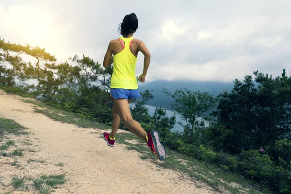 海辺を走るスポーツウェアトレイルのスポーティな若い女性 山でジョギングフィットネスの女の子 — ストック写真