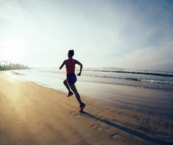 日出时在海滩上跑步的健身女性 — 图库照片