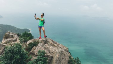  Başarılı Woman Hiker Seaside Mountain Top akıllı telefon ile fotoğraf çekmek