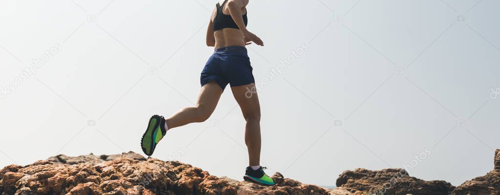 Woman running to rocky mountain top at seaside