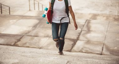 Kadın kaykaycı şehirde elinde kaykay ile yürüyor