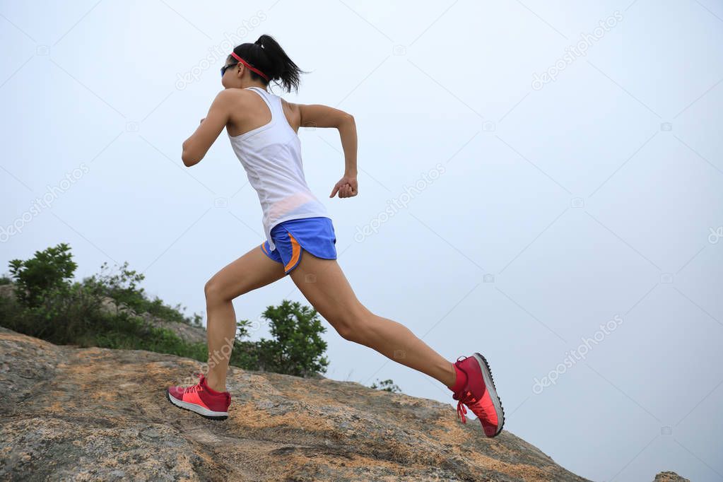 Young fitness woman running up to the seaside mountain top
