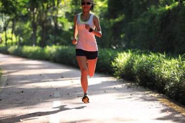 Yazlık park yolunda koşan kadın koşucu. Sağlıklı fitness kadın açık havada koşu.  