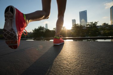 Sağlıklı yaşam tarzı, gündoğumu şehirde çalışan kadın koşucu bacaklar
