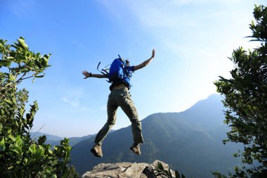 Başarılı genç kadın backpacker uçurumkenarında atlama