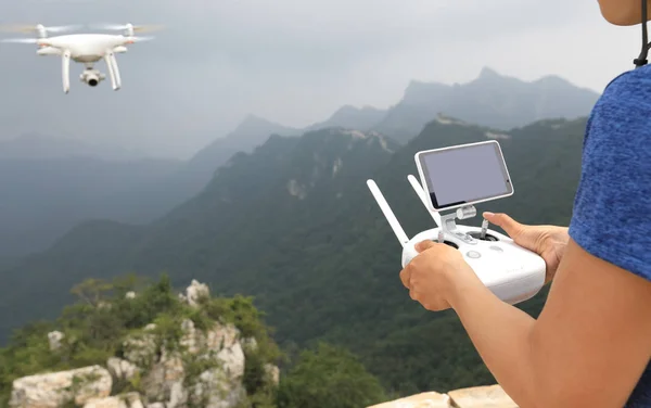 person controlling flying drone which taking photo of the great wall landscape in China