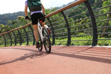 Orman yolunda dağ bisikleti süren bir kadın.