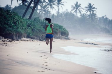 Fitness sağlıklı yaşam tarzı, genç kadın sabah gündoğumu sırasında tropikal plajda çalışan