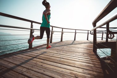 Sahil sahil üzerinde gündoğumu sırasında çalışan sportif kadın runner