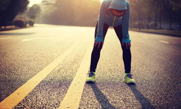 Tired woman runner taking a rest after running hard on city road