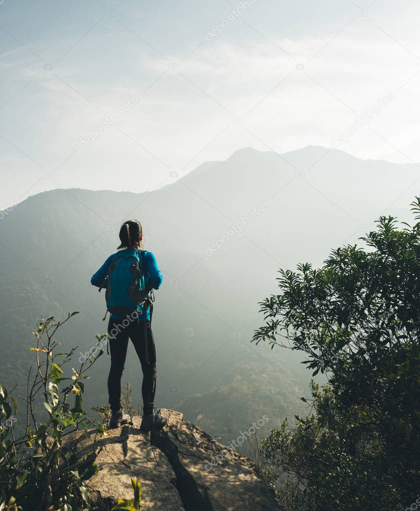 Successful hiker enjoy the view on sunrise mountain top cliff edge