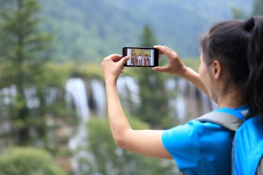 Akıllı telefondan fotoğraf çeken kadın turist. 