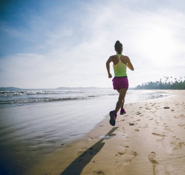 Güneş doğarken plajda koşan fitness kadın koşucusu 