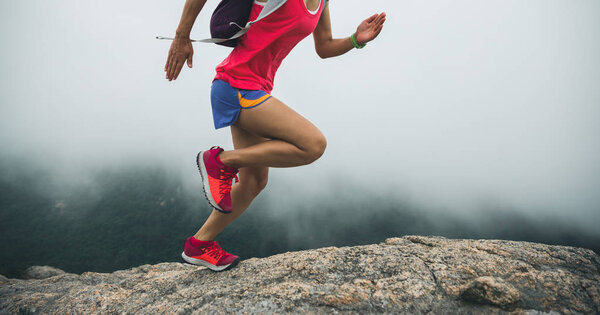 Woman ultra marathon runner running up to the seaside mountain top