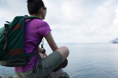 Sahil dağ zirvesinde oturan kadın yürüyüşçü 