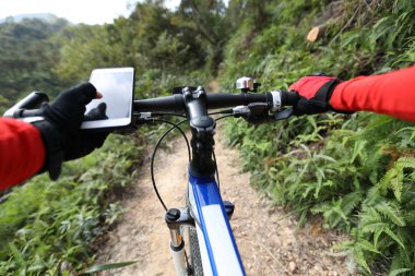 Yaz tepede sürme, cep telefonu tutarak, güneşli bir günde ormanda bisiklet sürerken Gps koordinatları arama için online uygulama kullanarak