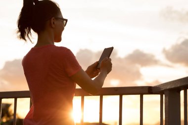 Gün batımında akıllı telefon kullanan kadın Hong Kong