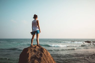 Deniz kenarında uçurumun kenarında duran kararlı kadın 