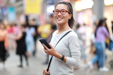 Şehirde akıllı telefon kullanan mutlu kadın