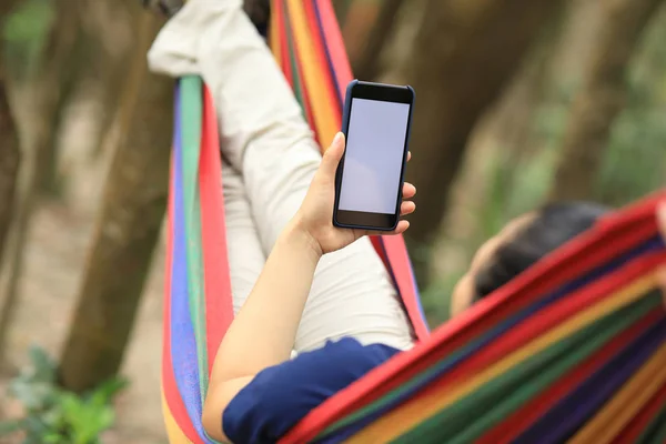 女人在吊床上放松与智能手机在森林 — 图库照片