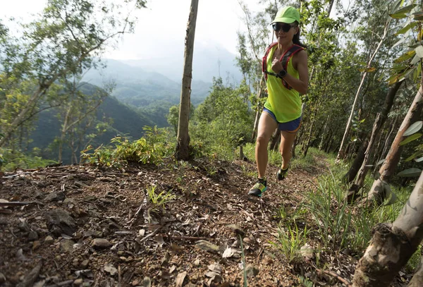 Sportswoman cross country ultra marathon trail runner running in forest