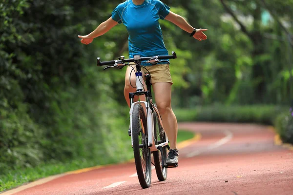 日当たりの良い公園のトレイルで自転車に乗っている女性は 手を使っていません — ストック写真