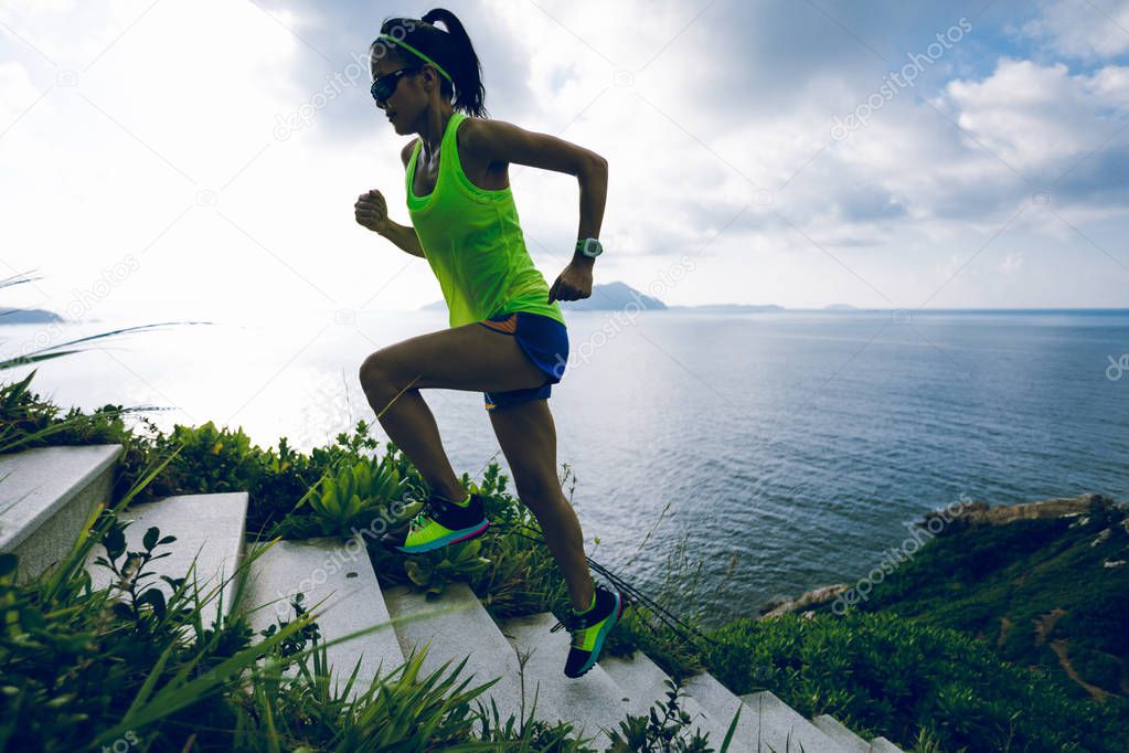 Determined woman running up on seaside mountain stairs