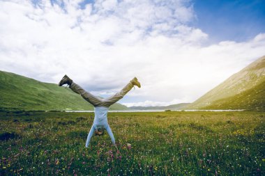 Yüksek rakımlı dağ çayırında bir handstand yapıyor kadın yürüyüşçü