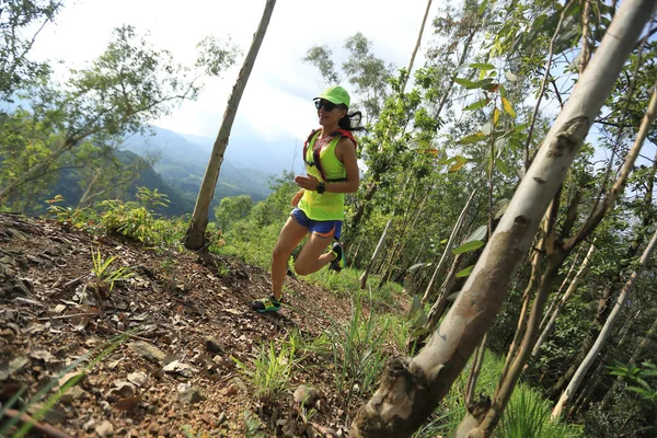 Sportswoman cross country ultra marathon trail runner running in forest